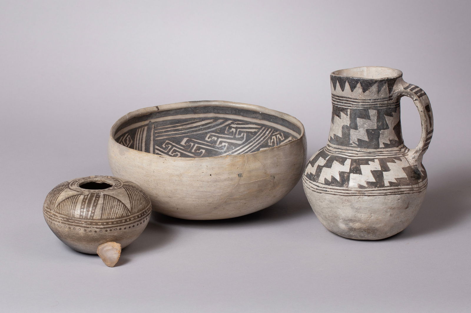 A Group of Three Ancestral Puebloan Pottery Vessels, including a Rare Chaco Keyhole Jug: A fascinating collection of three prehistoric Ancestral Puebloan (formerly Anasazi) black-on-white pottery vessels, highlighting the Kayenta and Chaco Canyon cultural traditions. All three vessels sho