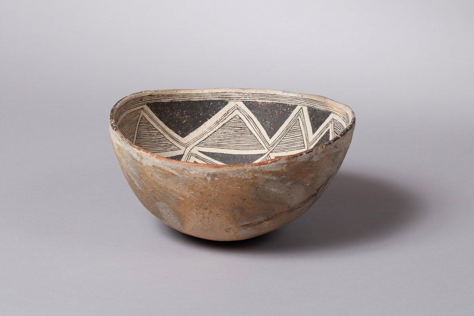 Classic Mimbres Geometric Bowl, Ca 1000 - 1130 AD: This Classic Mimbres black-on-white bowl, ca. 1000–1130 AD, is an exceptional example of Ancestral Puebloan pottery from the Mimbres Valley region of New Mexico. The bowl features a striking and int
