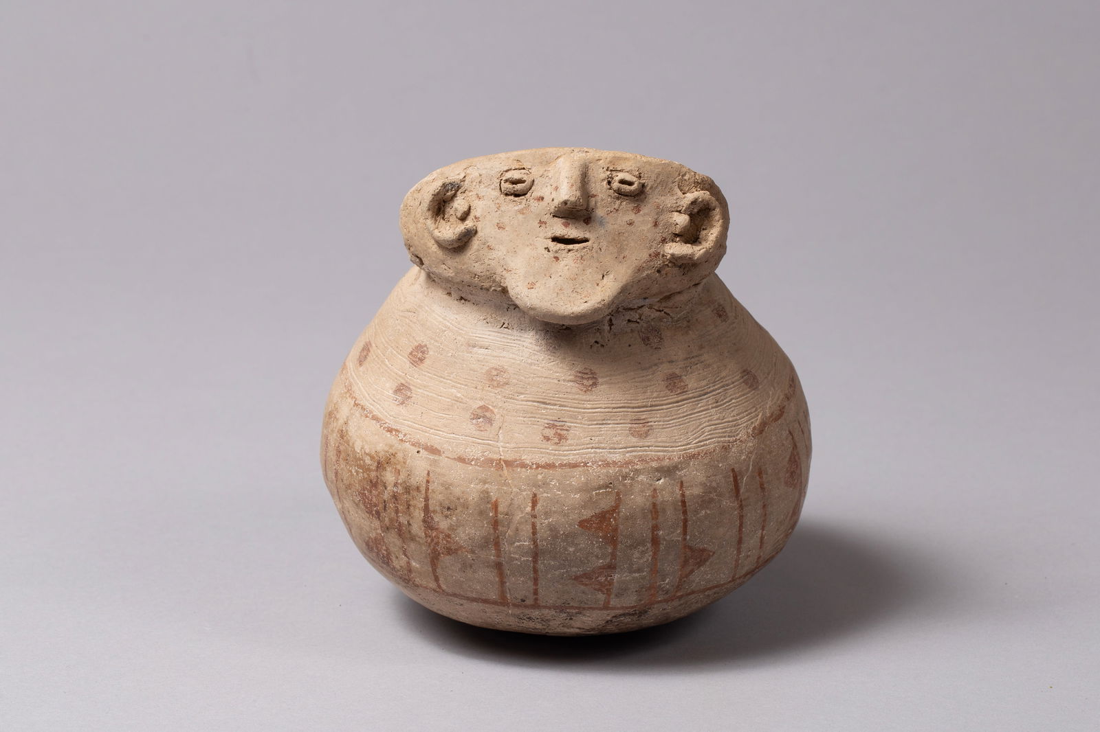 Scarce Hohokam Red on Buff Effigy Jar with Face, Ca 1150 - 1500: An exceptional and rare Hohokam face effigy jar from the Classic Period (approx. 1150–1500 CE), featuring red-on-buff painted designs. The vessel is a testament to the sophisticated pottery-making t