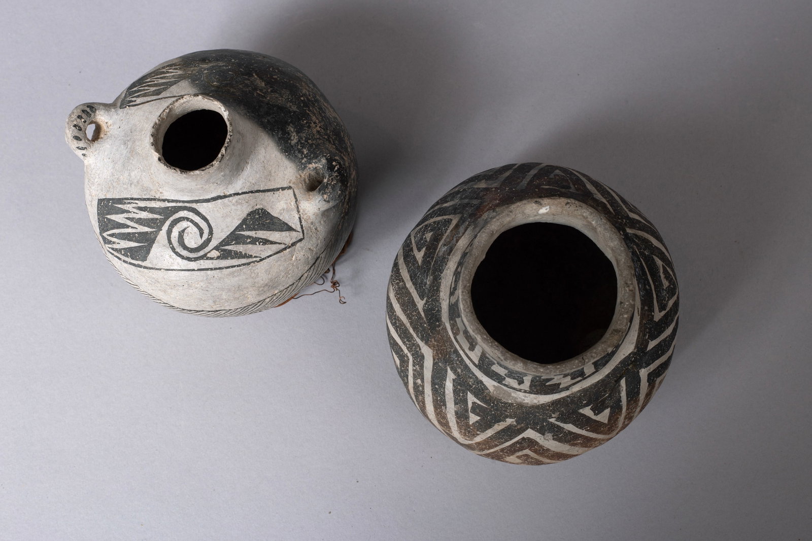 Two Black and White Anasazi Items: A Canteen and A Pitcher, Ca 1100 - 1300 AD: Lot of Two Pots:A.) Great Red Mesa Black and White Canteen 4 1/4"D, 4 1/2"D with handle, 4.5"H B.) Snowflake Black and White Pitcher 5"H, 5"H Provenance: Major & Nan Spessard Collection