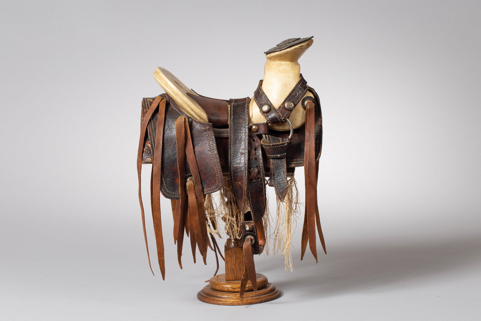 Mexican Salesman Sample Saddle, Ca 1800s: A true Mexican made salesman sample saddle, with covered horn, saddlebags, nickel decorations and a marked exposed teee, Included with a miniature rawhide braided quirt. Maker Marked "Fabricante/ Abra