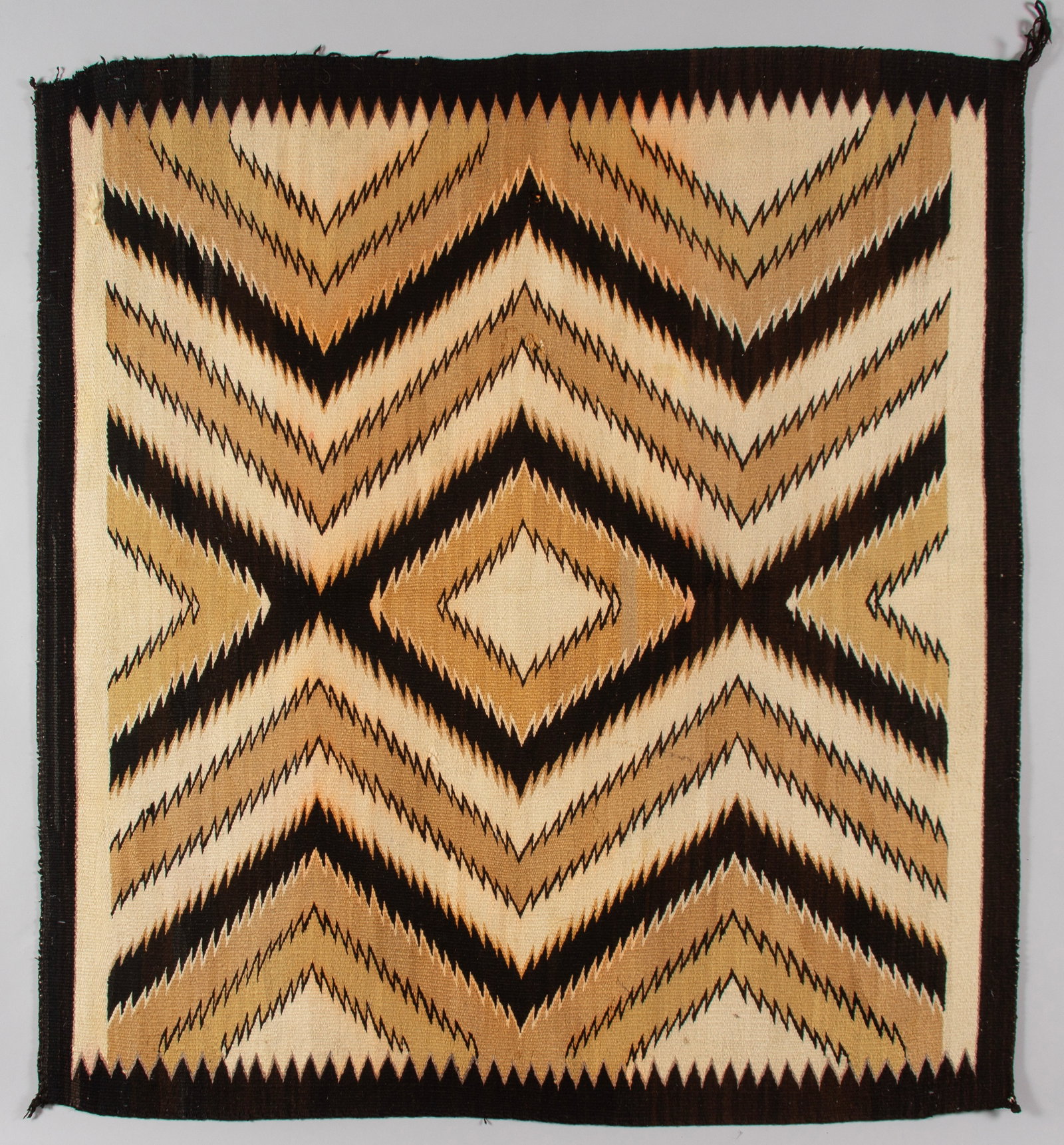 Vintage Navajo "Eye Dazzler" Rug, Natural Fleece Tones: This Navajo rug features a complex and dynamic geometric composition. The central design is dominated by large, interlocking serrated diamonds and bold zigzag patterns that traverse the full length an