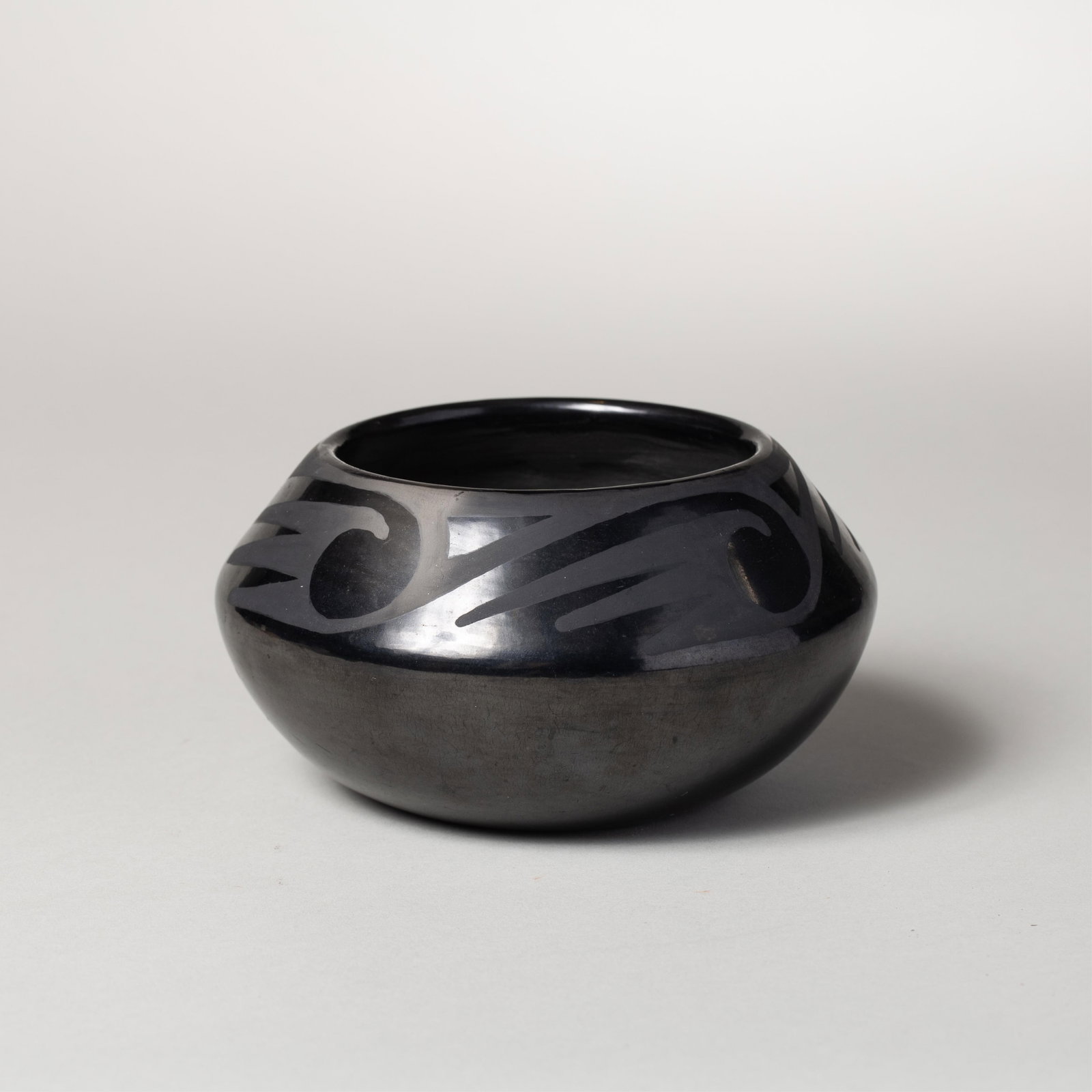 Maria & Santana Martinez, Blackware Pot: Blackware ceramic pot of squat form with wide shoulders and geometric motifs along the upper body. Signed "Maria + Santana" along the underside.