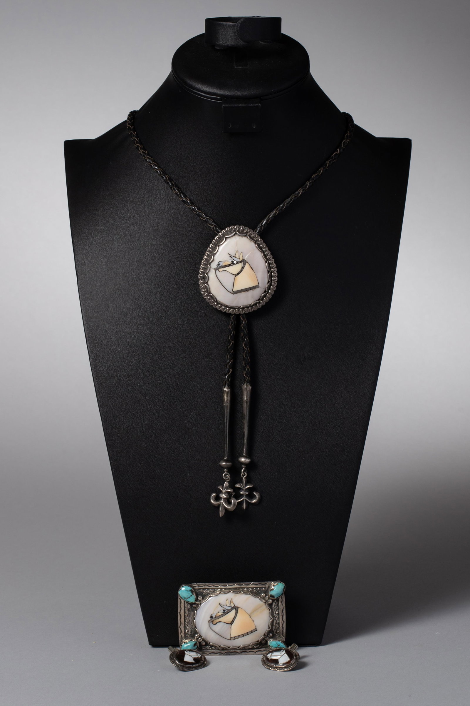 Dan Simplico Attributed Zuni Horse Head Inlay Jewelry Set ? Bolo, Buckle & Cufflinks: Early Zuni Inlay Horse Head Jewelry Set ? Attributed to Dan SimplicioZuni Pueblo, circa 1940?1960A Zuni inlay jewelry set attributed to Dan Simplicio, comprising a bolo tie, belt buckle, and pair of c