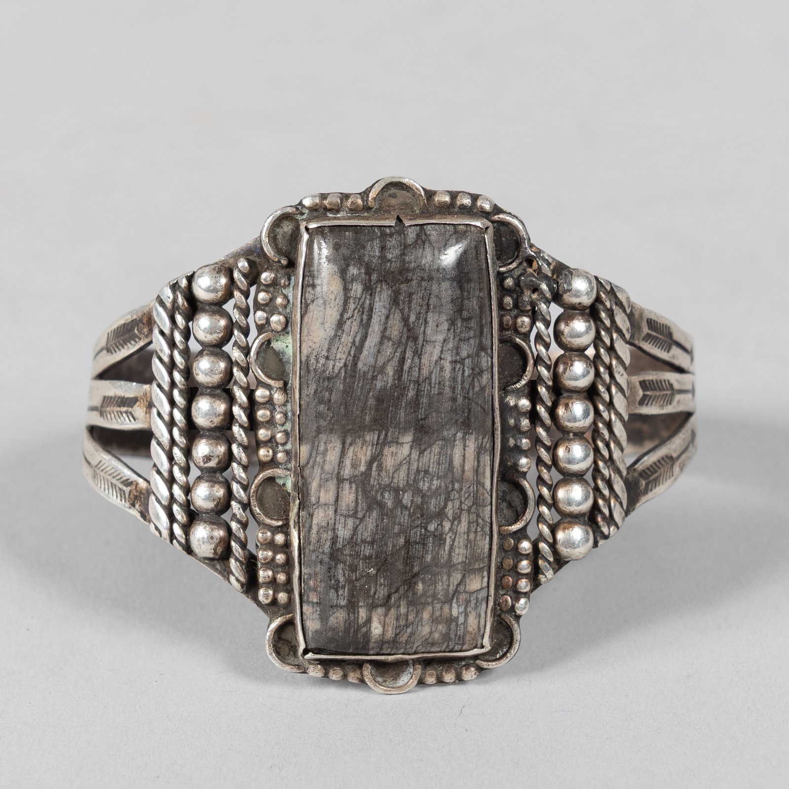 Navajo Dinosaur Bone Cuff Bracelet: An exceptional example of vintage Southwestern artistry, this striking Native American cuff bracelet showcases classic Navajo silversmithing techniques framing a rare prehistoric centerpiece. The heav