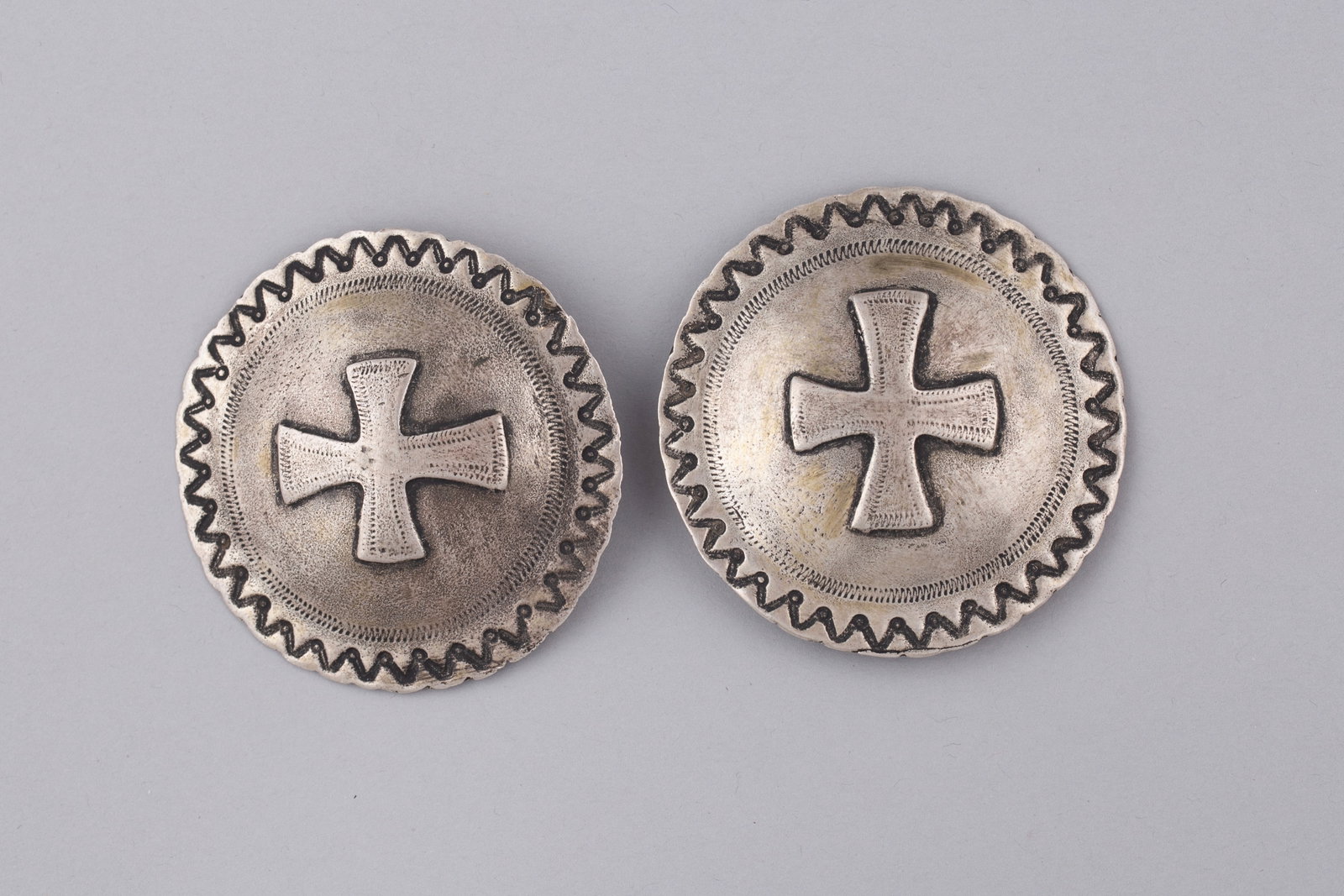 Navajo Bridle Conchas Sterling Silver with Cross Hand-Stamped: Each of domed circular form with applied cross motif at the center and scalloped border with darkened zigzag decoration around the edge.
