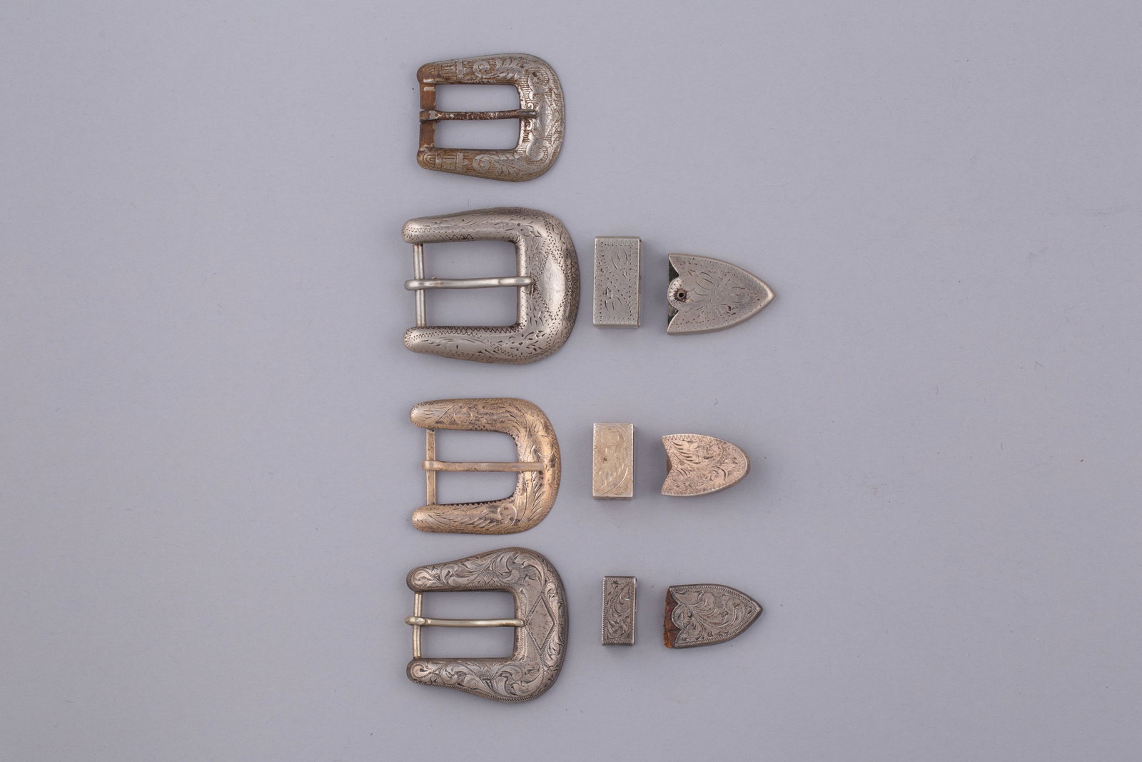 Four Sterling Silver Western-Style Buckles, Keepers & Tips: Set of four matching German-silver Western belt buckles with a clean polished finish and classic rectangular form. All retain original hardware and show consistent mid-century Western tack constructio