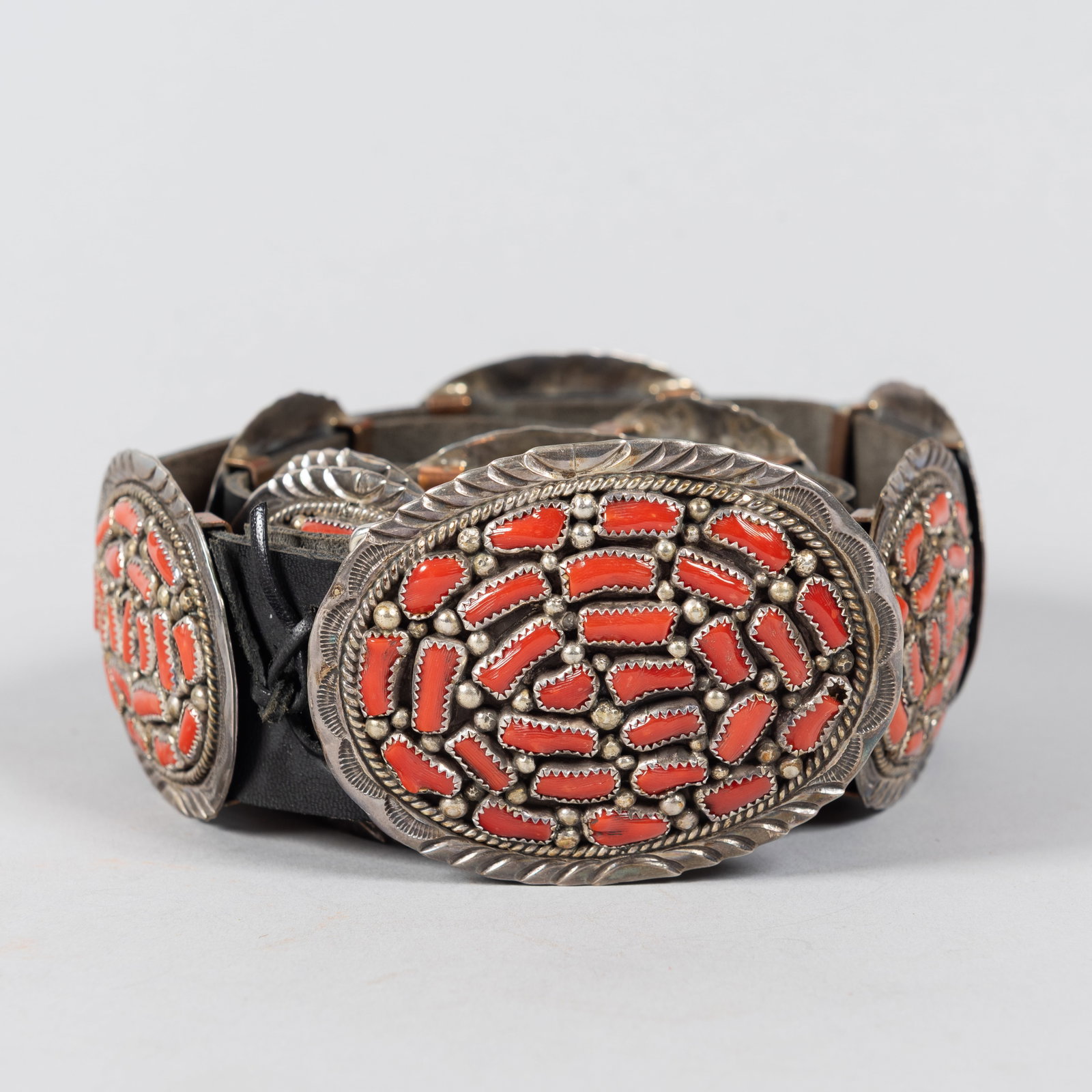 Vintage Native American Red Coral Sterling Silver Concho Belt, 2 1/2 x 3/4 x 46 1/2 in. (6.4 x 1.9 x: A striking vintage Southwestern Native American concho belt, crafted with extensive cluster work. The belt features heavily textured oval conchos and a matching focal buckle, each densely inlaid with 