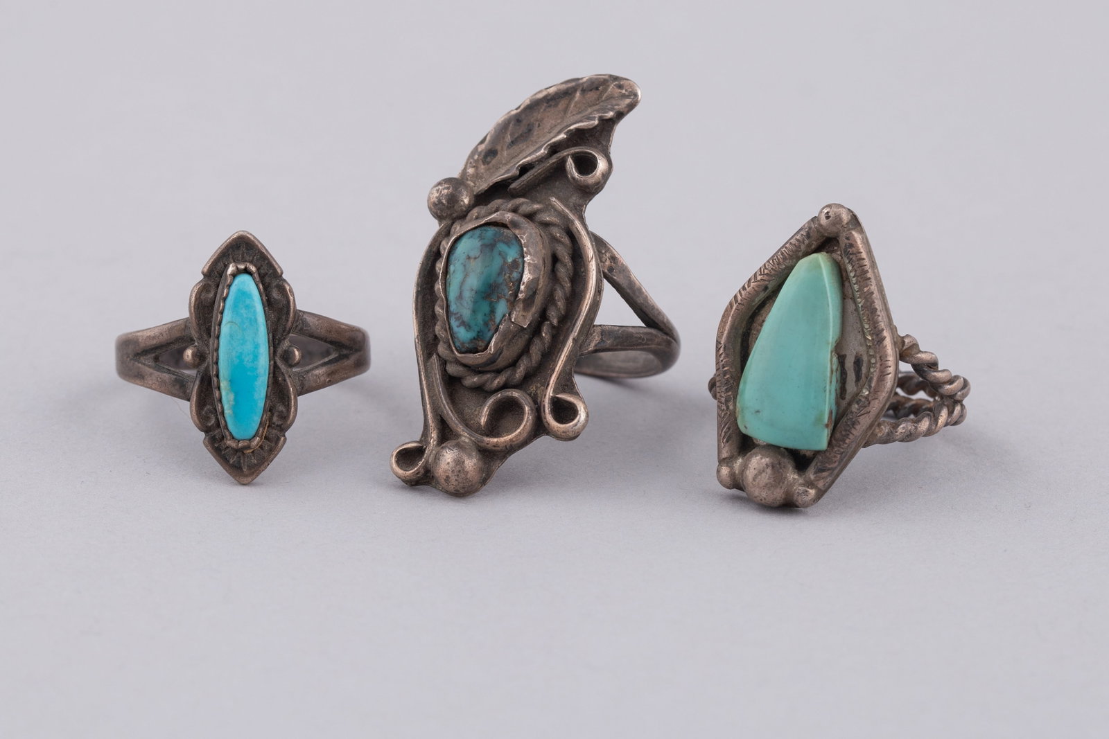 Three Vintage Navajo Sterling Silver & Turquoise Rings: An exceptional offering for collectors of Southwestern artistry, this lot features three vintage Navajo sterling silver and turquoise rings showcasing traditional tribal silversmithing techniques. Eac