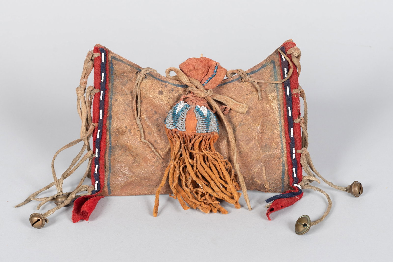 Blackfeet War Medicine Bundle with Beaded Paint Bag, James Economos Collection: The Blackfeet War Medicine Bundle represents a profound historical artifact of the Northern Plains. The central feature is a finely crafted, rounded hide medicine pouch, traditionally utilized to