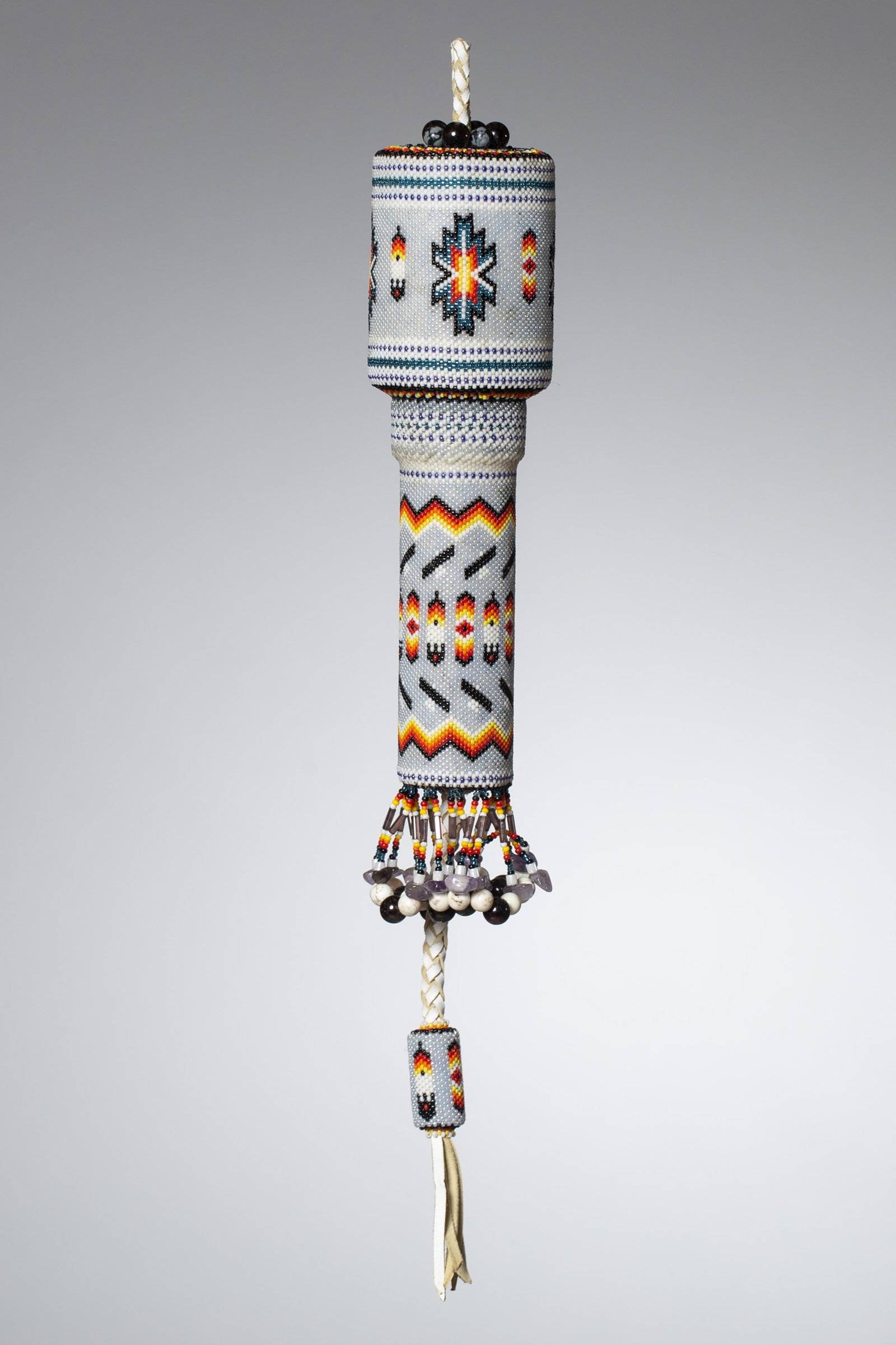 Native American Beaded Ceremonial or Peyote Rattle: Ceremonial Beaded Rattle Ceremonial rattle, constructed with a cylindrical rawhide body fully covered in multicolored glass beadwork. The surface decorated with geometric motifs including a central
