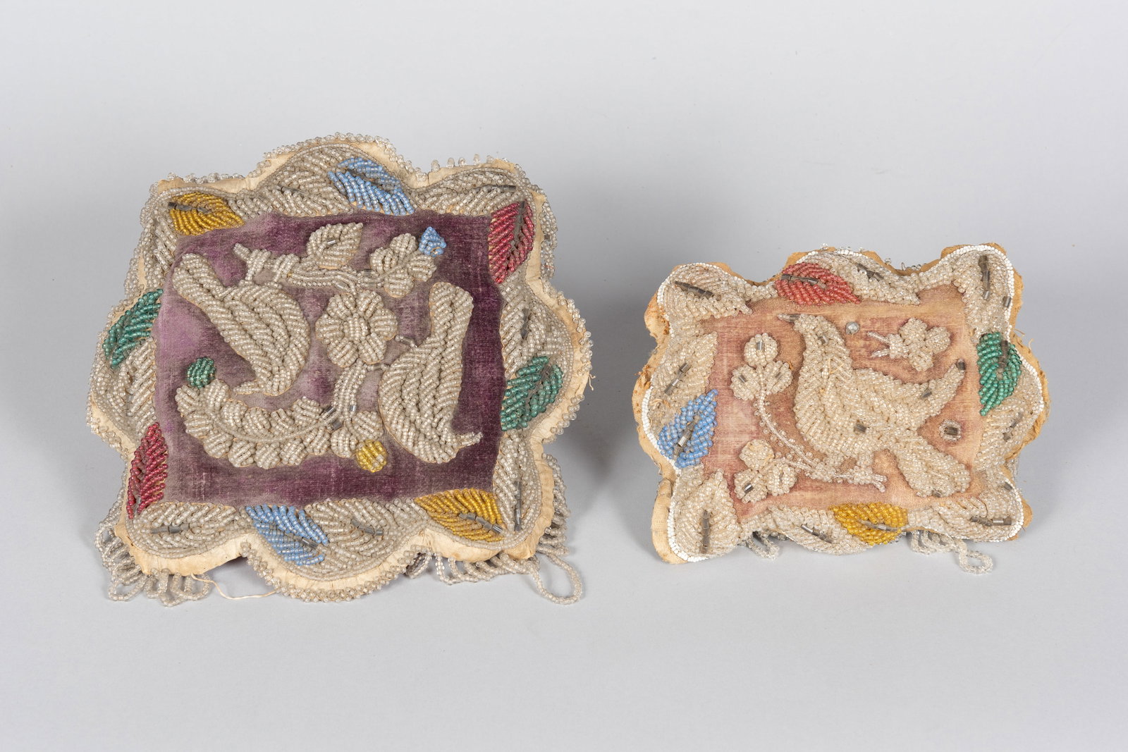 Two Plains/Great Lakes Beaded Pillows, Chippewa (Ojibwe), Victorian Period: A fine pair of late 19th-century Great Lakes beaded whimsy cushions, expertly hand-crafted by Chippewa (Ojibwe) artisans. Each cushion features vibrant velvet panels thickly decorated in a classic