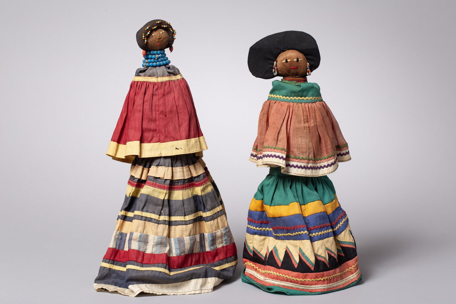 Pair of Vintage Seminole Palmetto Fiber Dolls: A charming pair of authentic, handmade Seminole Indian dolls. Each figure features a body and head meticulously formed from harvested saw palmetto fiber, a material chosen by artisans to naturally