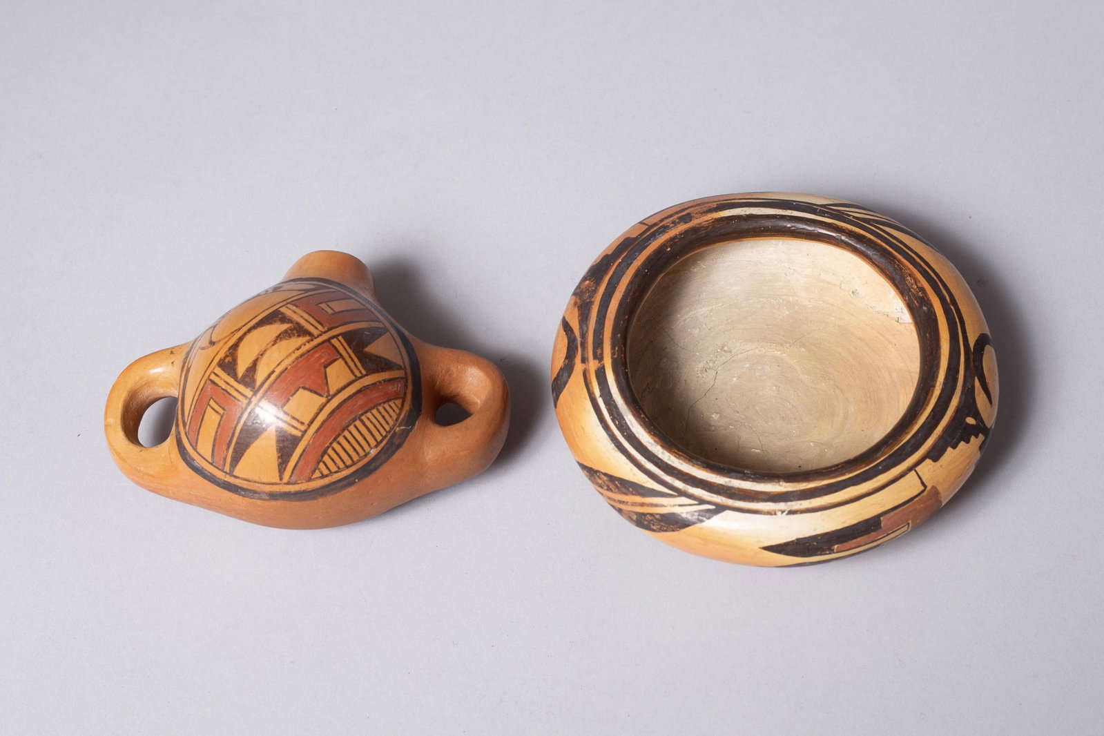 Group of Two: Hopi Canteen by Emily Naha and Nampayo Family Pottery Vessel: 1) Emma Naha Polychrome Hopi-Tewa Canteen, This traditional hand-coiled canteen is a fine example of late 20th-century Hopi-Tewa pottery by Emma Naha (Hopi, b. 1930s/40s, active since 1970). Naha, a r