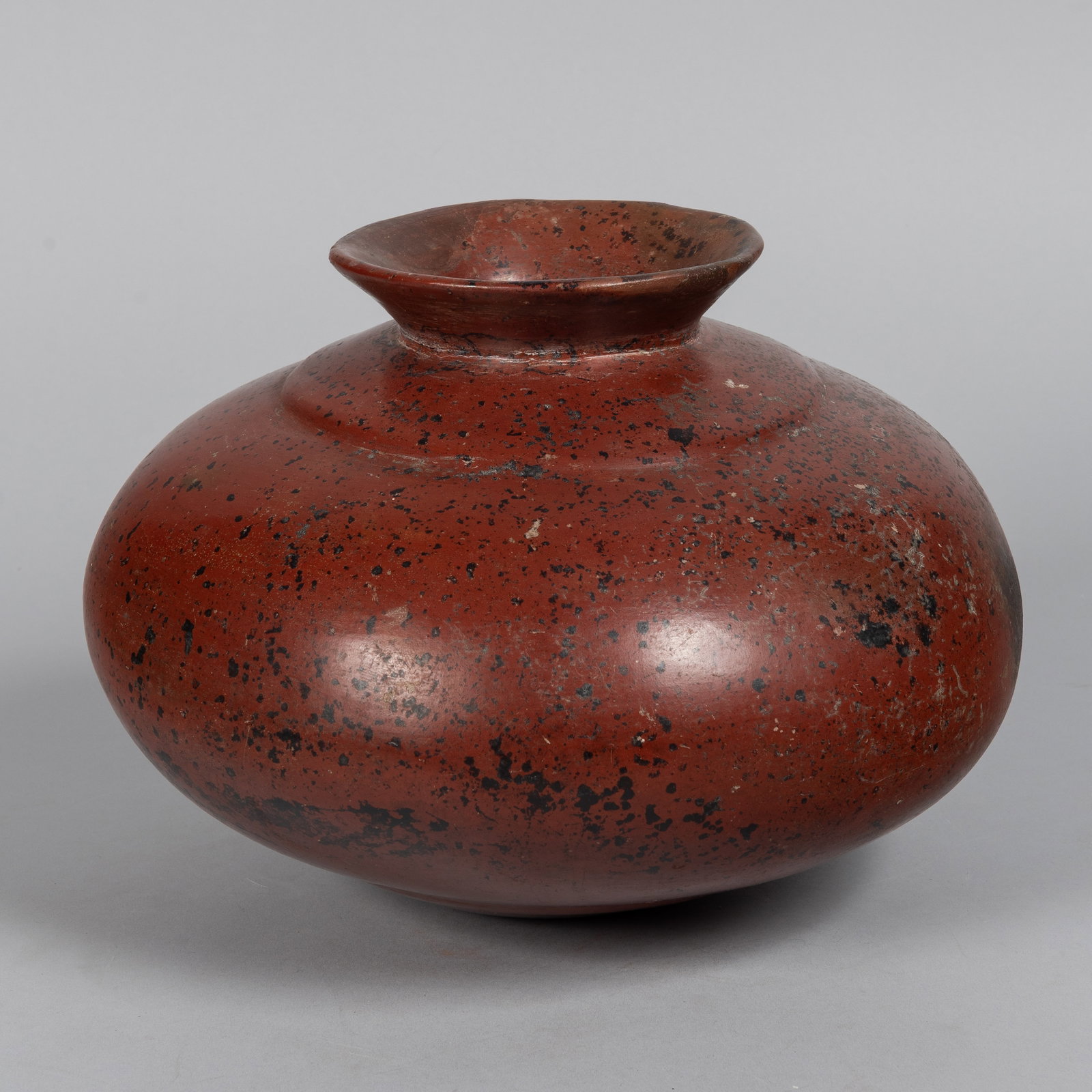 Colima Pre-Columbian Pottery Jar, Ca 150 B.C.: The elegant, undecorated globular vessel features subtle recessed shaping at both the top and bottom of its body, rising gracefully to a wide, dramatically flaring lip. Coated in a classic rich, dark 