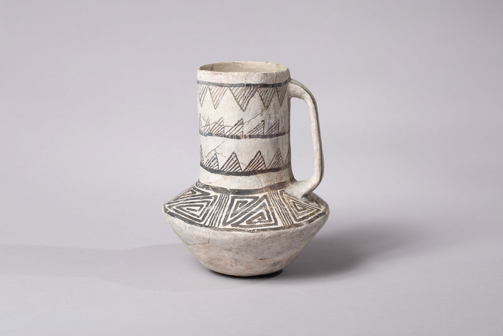 Mesa Verde Tall Neck Pitcher: This ceramic vessel is a classic example of a Mesa Verde-style pitcher, a hallmark artifact of the Ancestral Puebloan culture. It features a cylindrical body with a flat base and a broad, vertical str