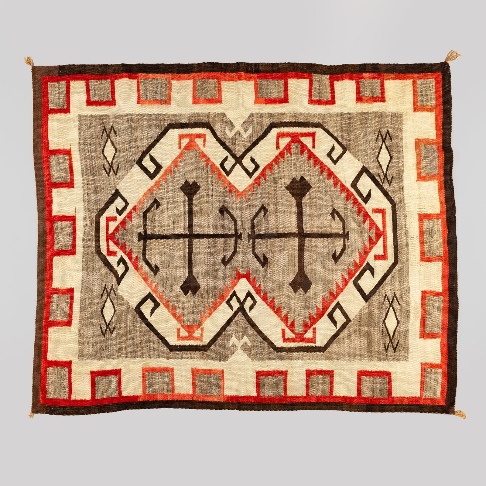 Navajo Crystal Regional Rug, Ca. 1930s-1940s: A finely woven Navajo regional textile from the Crystal Trading Post area, displaying a striking variation of the classic Storm Pattern. The central field features stacked, geometric diamond and hourg
