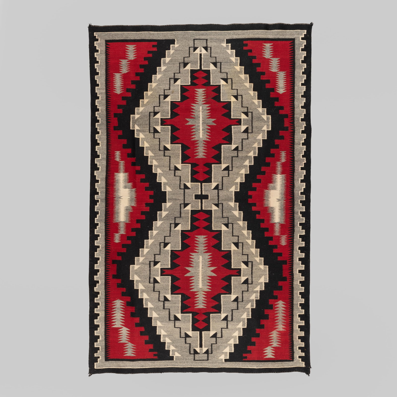 Ganado Rug 45 1/2 x 71 1/2 in. (115.6 x 181.6 cm.): A striking mid-20th-century Navajo regional textile woven in the classic Ganado style, popularized by John Lorenzo Hubbell. This handwoven wool rug features an elongated double-diamond central motif a