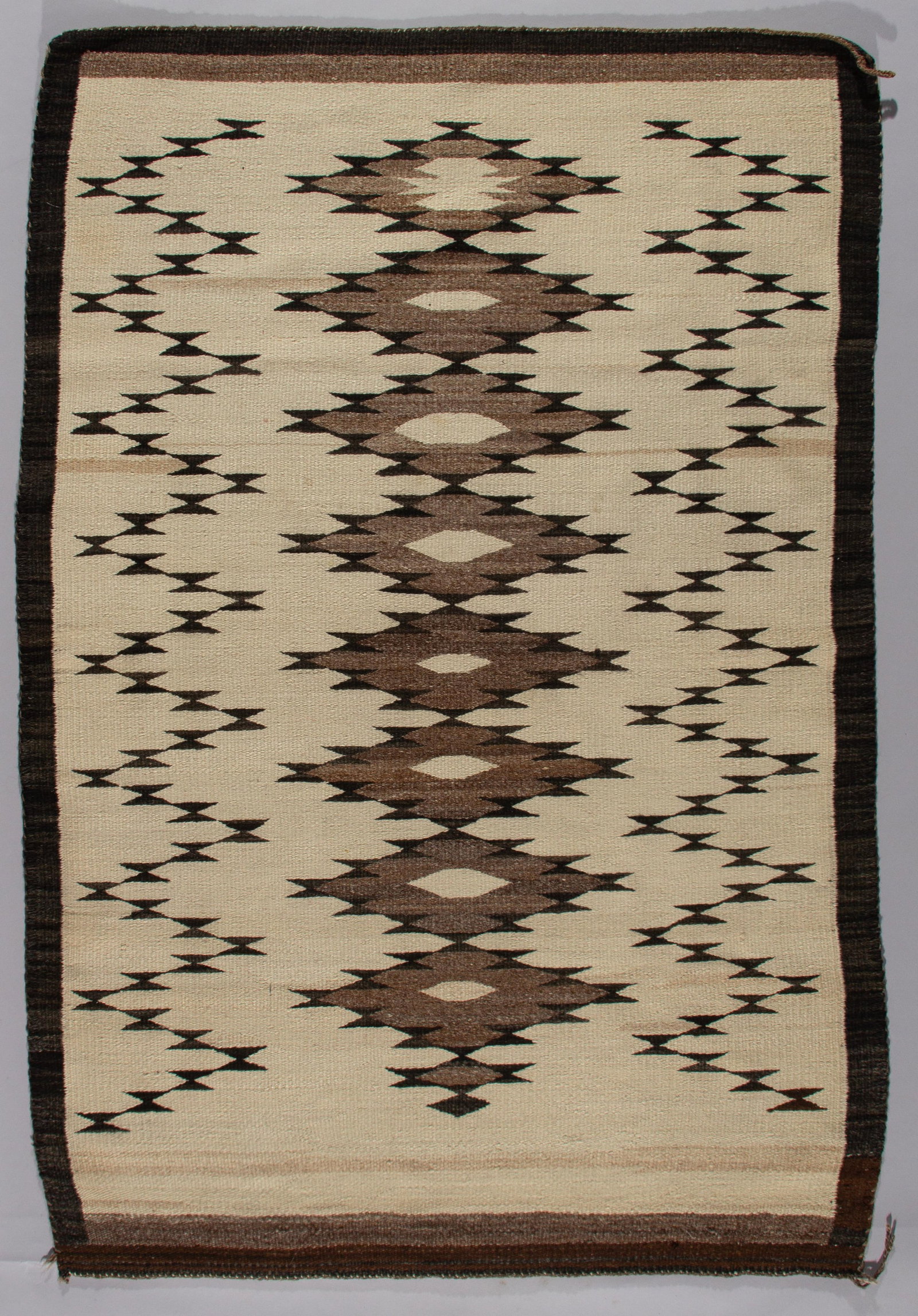 Navajo Van Winkle Butterfly: A classic Navajo weaving, circa 1920s, featuring a bold central band of serrated diamonds. This textile showcases the full spectrum of natural, undyed hand-spun fleece, with the cream-colored ground s