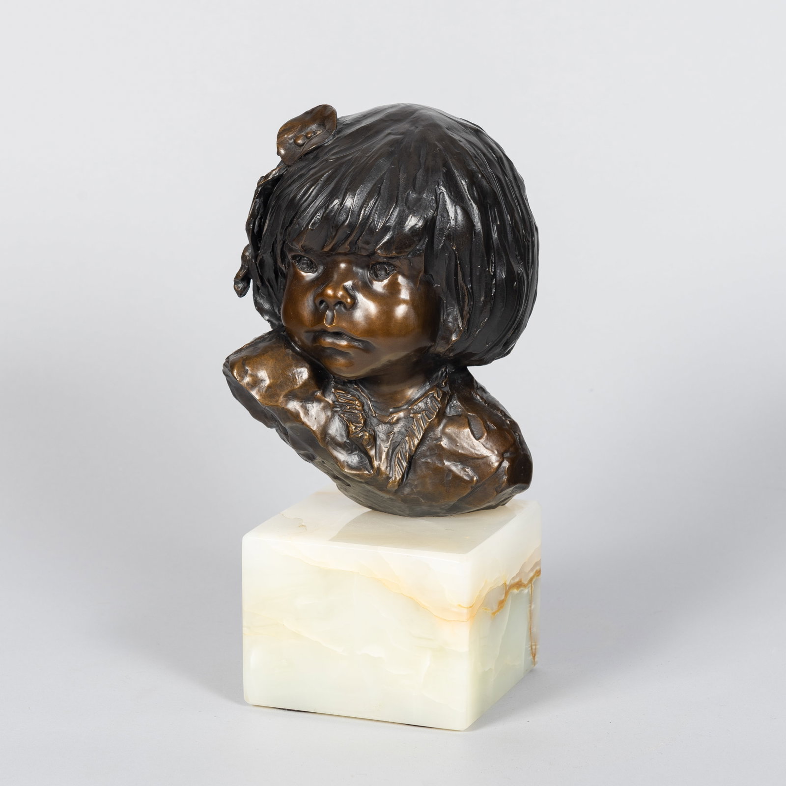 Glenna Goodacre (1939 - 2020), Two-Piece Collection: Bronze Sculpture and Framed Drawing of a Young: A heavily patinated bronze bust of a child. The piece exemplifies Goodacre's distinct textural modeling style, emphasizing fluid lines, expressive features, and a rich, multi-toned surface finish. Ins