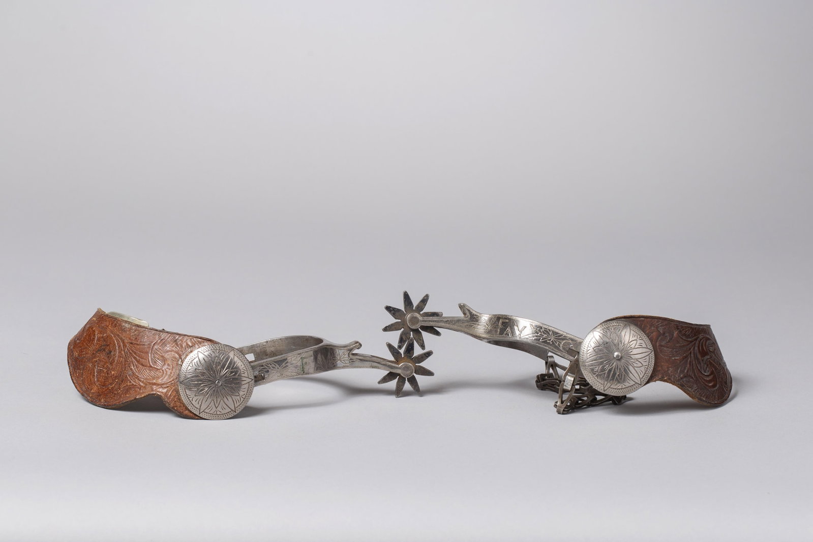 Vintage Single-Mounted Prison-Made Spurs, Custom Engraved "Fay" with Silver Conchos: A unique pair of historic Western cowboy spurs, exhibiting the classic structural and stylistic hallmarks of a "Prison-Made" origin. The exterior is hand-engraved with the personalized name "FAY" in e
