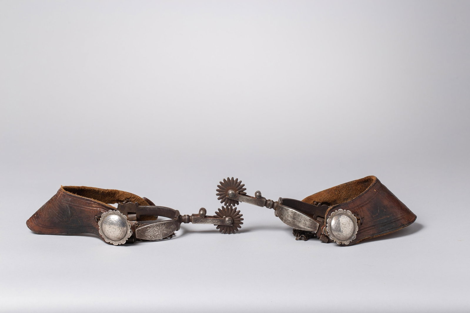 Antique Silver Engraved Spurs: These antique silver-engraved spurs feature craftsmanship characteristic of early 20th-century Wyoming or Northern Plains makers. Intricate silver overlay featuring classic Western scrollwork and flor
