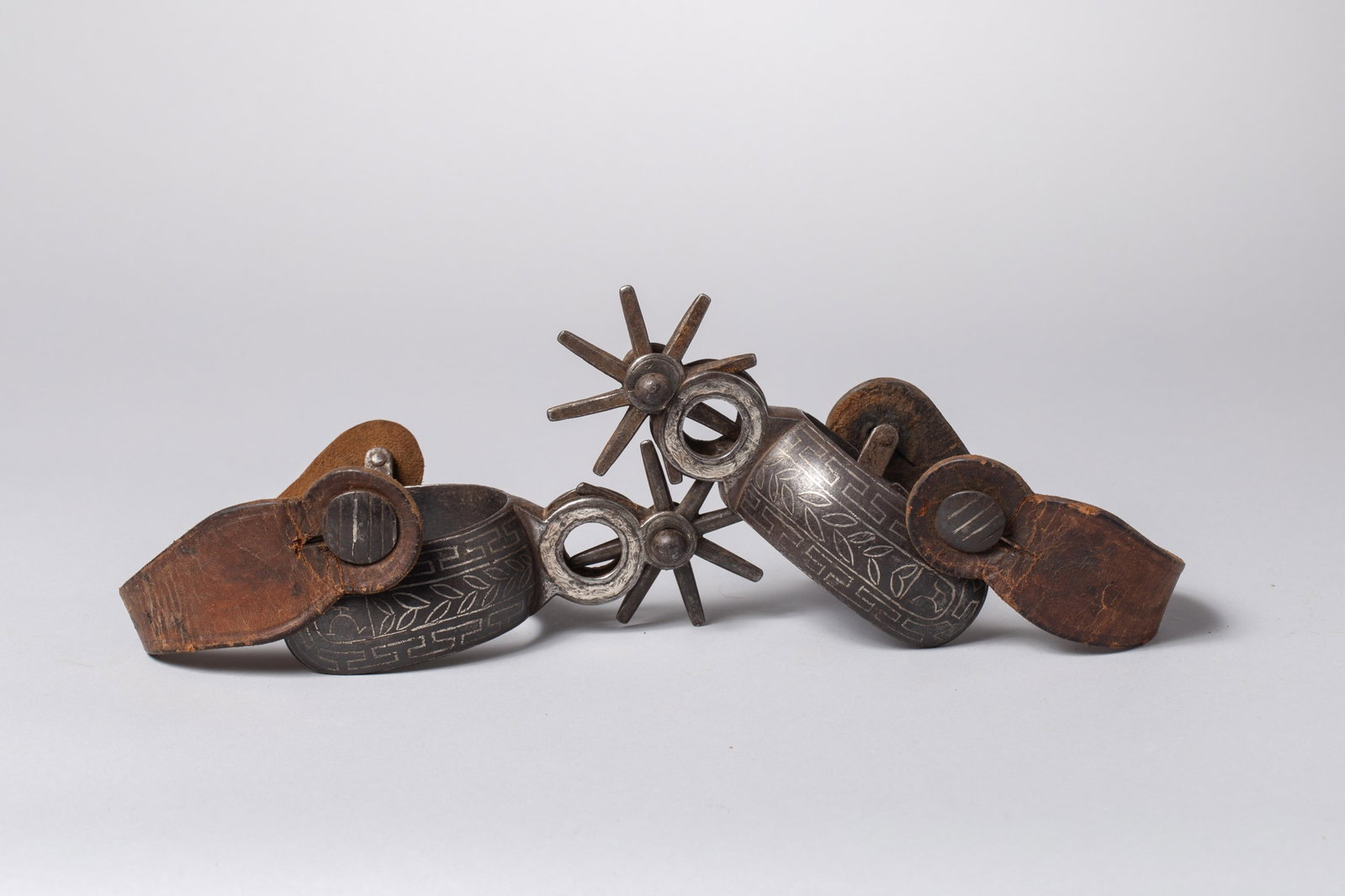 Antique Mexican Charro Silver Inlaid Iron Spurs: The wide, robust heel bands feature classic inlaid geometric and foliate design detailing on the outside heelband. Impressive 8-point star rowels. Equipped with its period authentic, heavy dark brown,