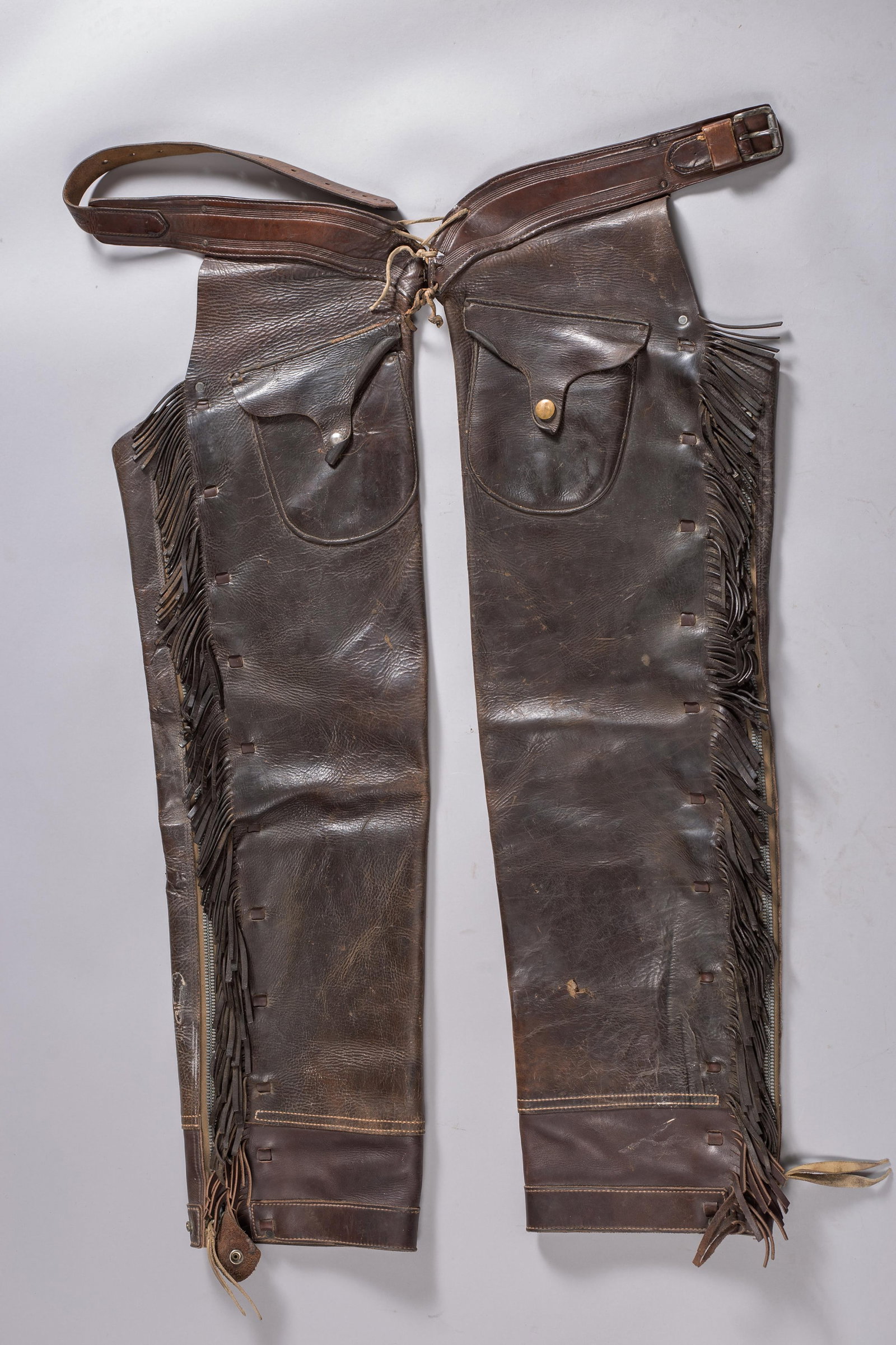 H.H. Heiser Fringed Shotgun Chaps, Denver CO: An exceptional pair of antique Western cowboy shotgun-style leather chaps produced by the legendary Hermann H. Heiser Saddlery Company of Denver, Colorado. Crafted from premium, heavy dark brown