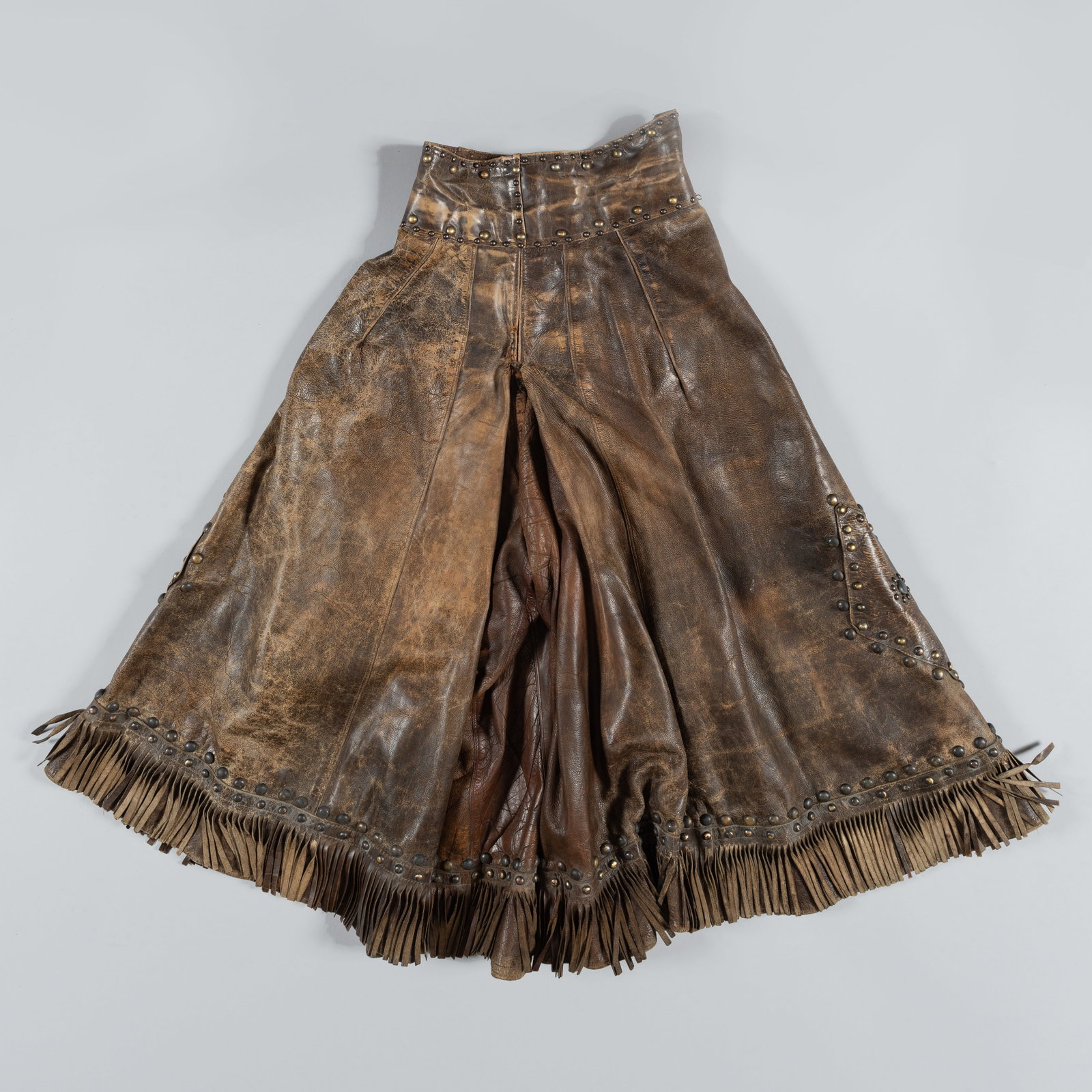 Antique Ladies' Leather Split Leg Riding Skirt: A remarkable piece of early 20th-century Western Americana: a ladies' leather split riding skirt (culottes). Designed for the transition from sidesaddle to riding astride, this functional garment