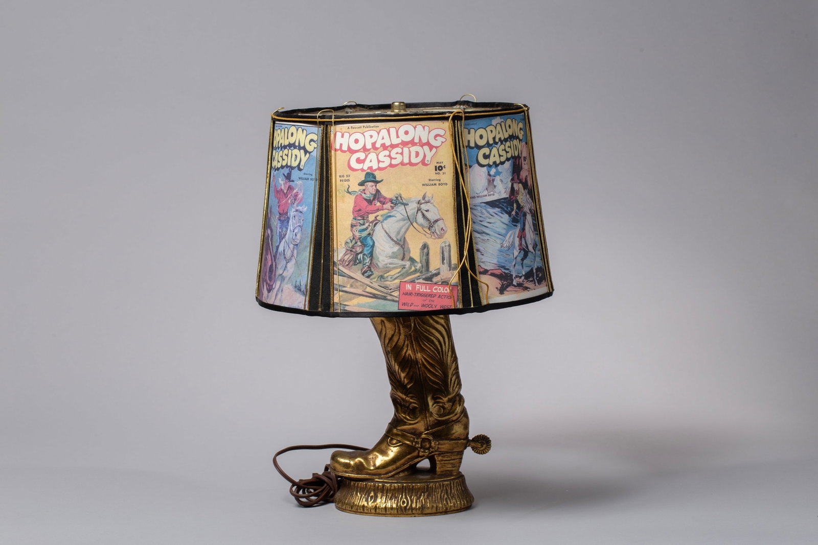 Vintage 1950s Hopalong Cassidy Western Boot Table Lamp with Original Comic Style Movie Posters Shade: This rare find features a detailed, dimensional cowboy boot base complete with textured stitching details and a realistic spur at the heel. The base boasts a striking metallic bronze finish that remai