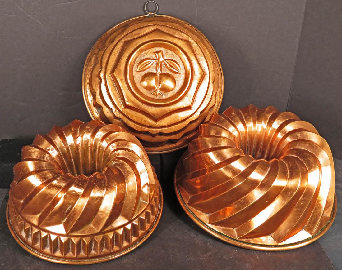 Three Large Vintage Copper Kitchen Molds: Three Large Vintage Copper Kitchen Molds. 2 molds have center cones 9 1/2 and 11 inch diameters. Solid center mold has embossed fruit in center, 10 inch diameter.