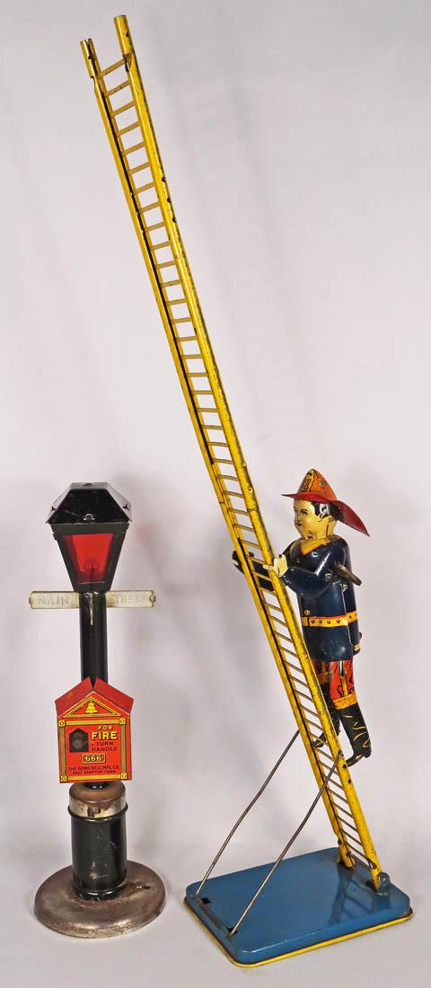Two Vintage Tin Fire Toys: Two Vintage Tin Fire Toys. 1940's Louis Marx "Smokey Joe" Fireman Windup Climber and Lamppost Sign with Fire Box. Overall good non-working condition. Lamppost measures 11 1/2 inches tall.