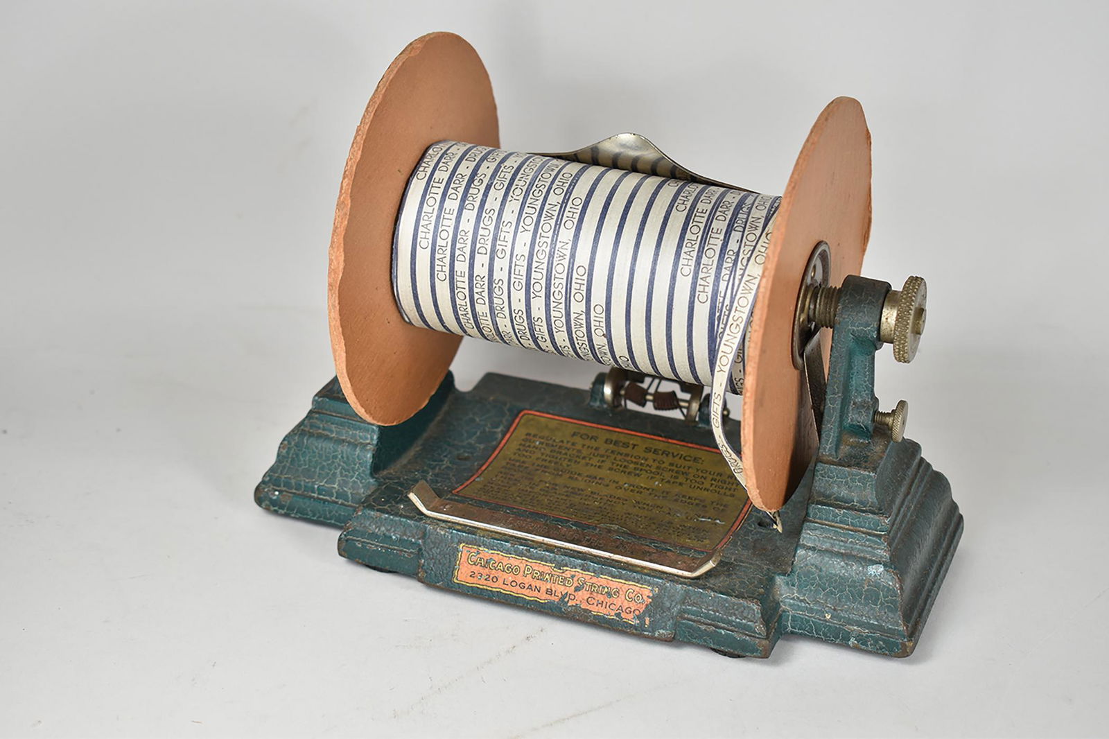 Country Store Cast Iron Printed Ribbon Dispenser: Drug Store Cast Iron Printed Ribbon Dispenser. Mfg. by Chicago Printed String Co. Ribbon on spool for printed for Charlotte Darr Druggist, Youngstown, Ohio. 8 1/2 X 6 X 4 1/2 inches.