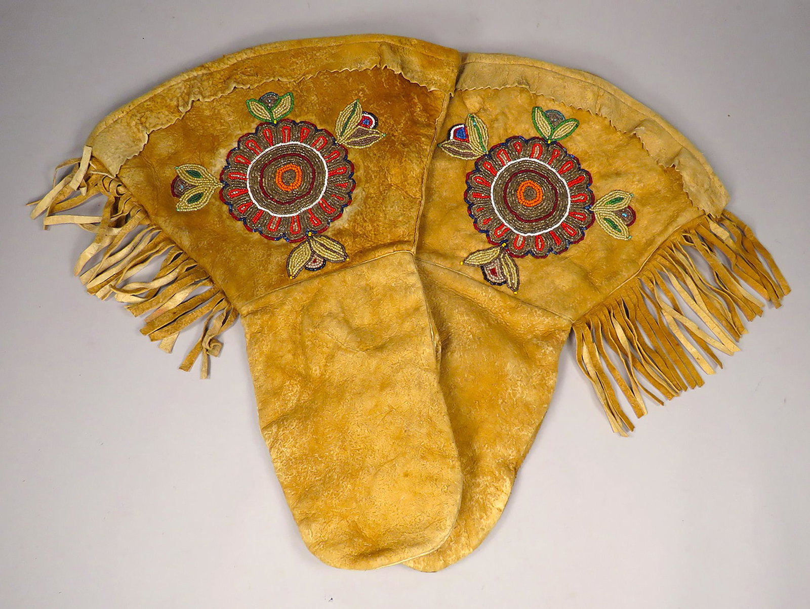 Early Native American Indian Beaded Gauntlets: Early, Native American Indian Beaded Mittens. Sunburst and Floral Decoration with Cuff Fringe and Skirt. Good overall condition.