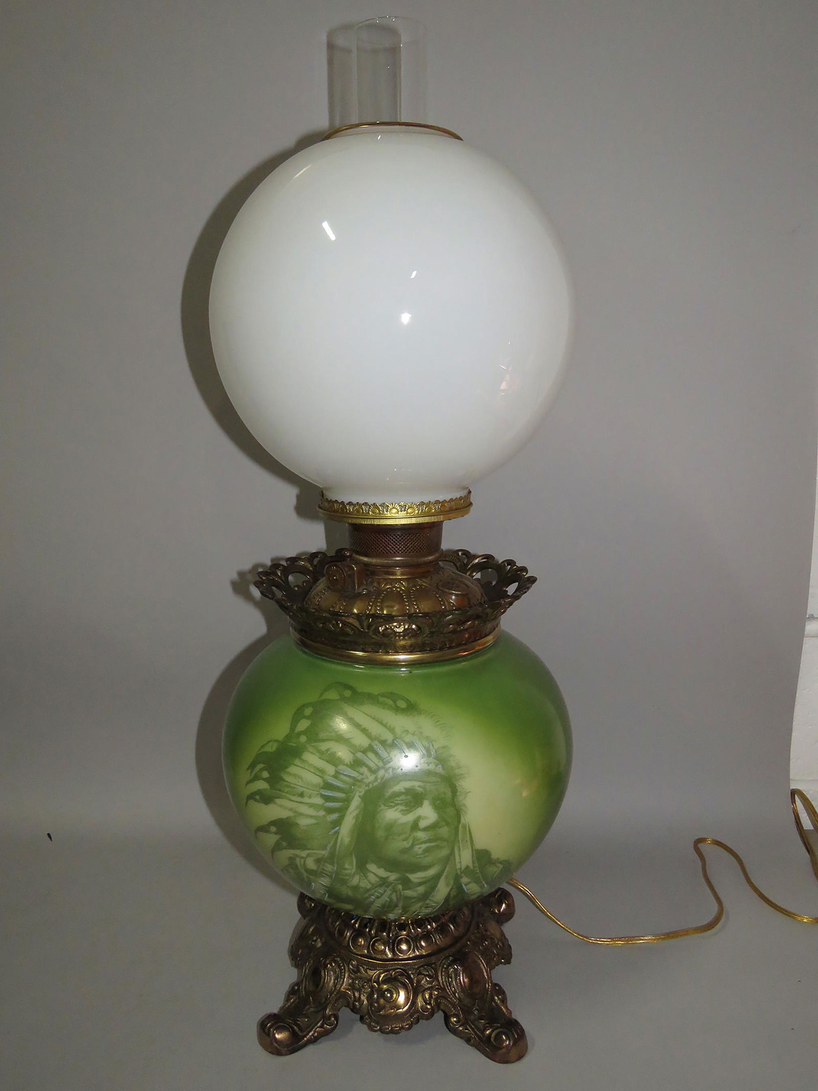 Antique Victorian Gone with the Wind Lamp: Antique Victorian Gone with the Wind Lamp. Hand painted base with Native American Indian image, green. Replacement milk glass top globe. Electrified working condition. Ornate cast iron base. 24 inches
