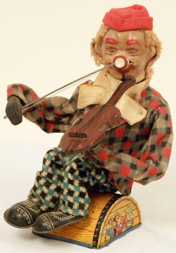 Early "Clown Playing Fiddle" Battery Operated: Early "Clown Playing Fiddle" battery operated w/tin base. Made in Japan by "Alps". Clown's face has some damage around nose and tip of fiddle has been repaired otherwise good condition. 7 X 10 1/2 X 3