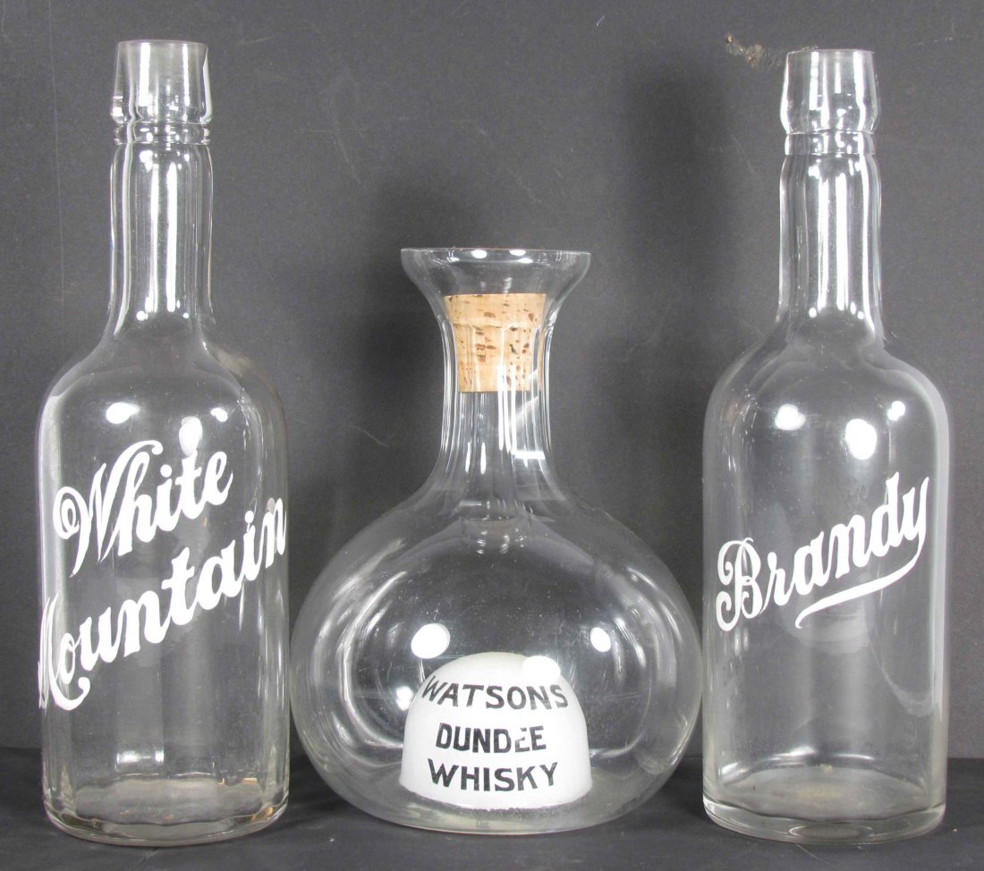 Three Back Bar Bottles: Three Back Bar Bottles. White Fountain and Brandy have enameled labels. Very unusual interior dome with advertising in bottom for Watson's Dundee Whisky. No chips or cracks. Watson's measures 8 1/ 2 i