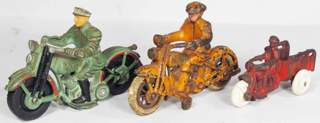 Three Cast Iron Toy Motorcycles: Three Cast Iron Toy Motorcycles. Orange Harley Davidson, Arcade Green Patrol and Red Crash Car. Good overall original condition. Patrol measures 6 1/2 inches long.