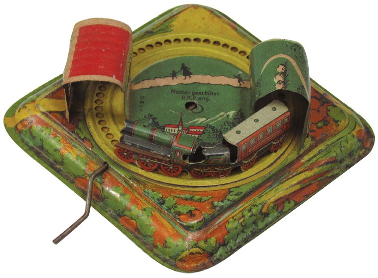 German Tin Litho Mechanical Toy: German Tin Litho Mechanical Toy. Train with mountain tunnel and station. Very good non-working condition. 3 3/4 inches square X 1 1/2 inches tall.