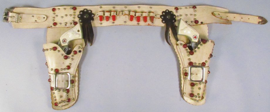 Pair of Hubley Texan Jr. Toy Cap Guns in Gun Rig: Pair of Hubley Texan Jr. Toy Cap Guns in Gun Rig. White leather with red stud trim. Guns in excellent condition.