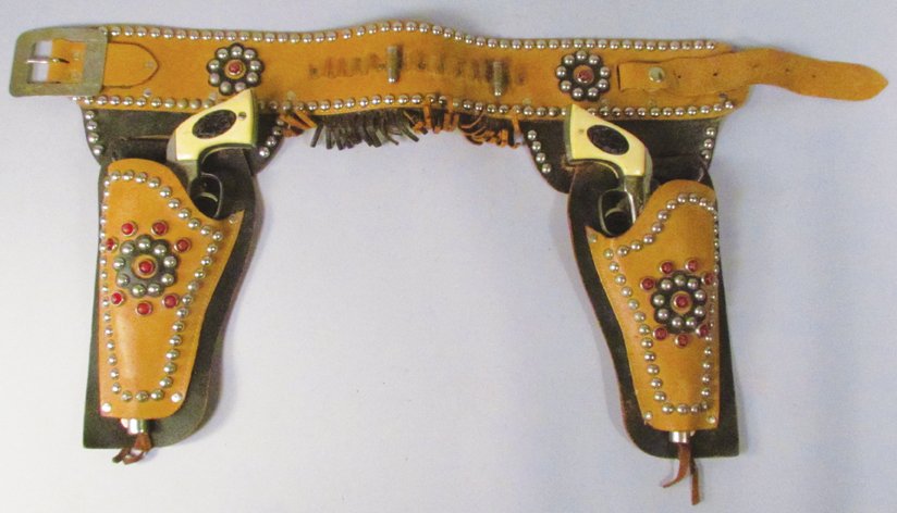 Pair of Hubley Marshall Toy Cap Guns in Gun Rig: Pair of Hubley Marshall Toy Cap Guns in Gun Rig. Lt brown and black studded rig with fringe. One gun has corner chip otherwise overall good condition.