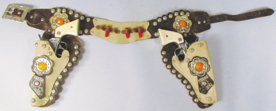 Pair of Nichols Stallion 38 Toy Cap Guns and Rig: Pair of Nichols Stallion 38 Toy Cap Guns and Gun Rig. Brown and white hand tooled leather with amber jewels, left side holster is detached on one side otherwise overall very good condition.