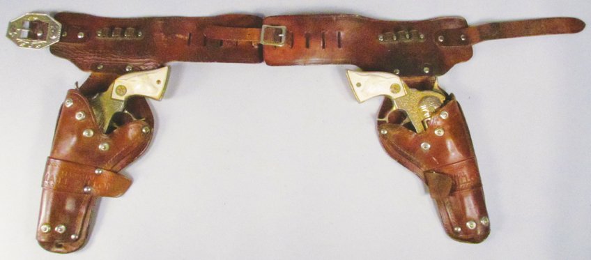 Pair of Hubley Texan Toy Cap Guns in Gun Rig: Pair of Hubley Texan Toy Cap Guns in Gun Rig. Tooled leather "Gunsmoke" Holster. Overall playwear.