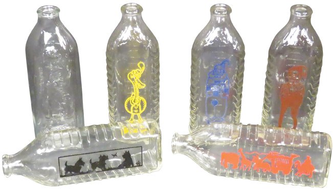 Enameled Glass Baby Bottles: Enameled and Embossed Glass Baby Bottles. (6) various designs. No chips or cracks. 6 7/8 inch diameter.