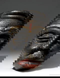Ibibio wood dance mask: Early 20th century large wooden mask with articulated jaw and bold features characteristic of the Ibibio culture. Lustrous black pigment with red and beige highlights. Carved with a headband that look