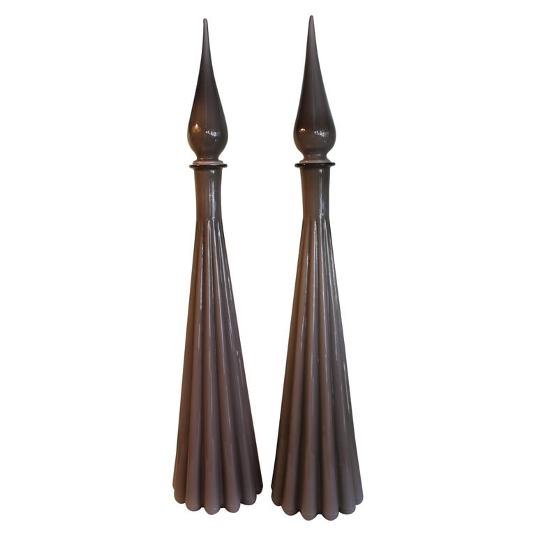 Pair of Murano Cased Glass Decanters with Stoppers: Pair of Italian cased glass decanters with stoppers. One bottle has a label that reads Made In Italy. They each measure about 20" high (without stoppers) and 28" high with stoppers. Diameter at base i