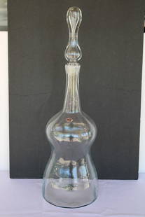 Blenko Clear Vessel with Stopper and Label: Blenko hand blown clear vessel with stopper and label. Vessel measures 27.5" with stopper, 20" without and 8.25" diameter. Stopper is 8.5" tall. Manufactured by Blenko, USA. Blenko Glass Company is an
