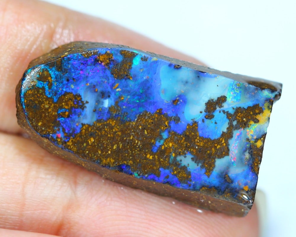 23.84-Carat Boulder Opal Rough from Winton, Queensland: This auction lot of 23.84-carat boulder opal rough from Winton, Queensland, measuring 29.5x15.4x5.8 mm, exemplifies the untamed beauty and vivid play-of-color characteristic of Australian opals. Bould