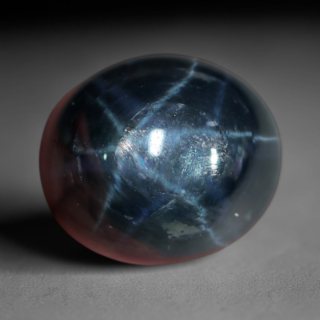 12.33 Carats Deep Midnight Star Sapphire Oval Cabochon - Natural Loose Gemstone, 33XC: This substantial star sapphire showcases a rich, deep midnight blue hue, creating a dramatic backdrop for its vivid, well-defined six-rayed star. The star's bright, crisp rays radiate across the smoot