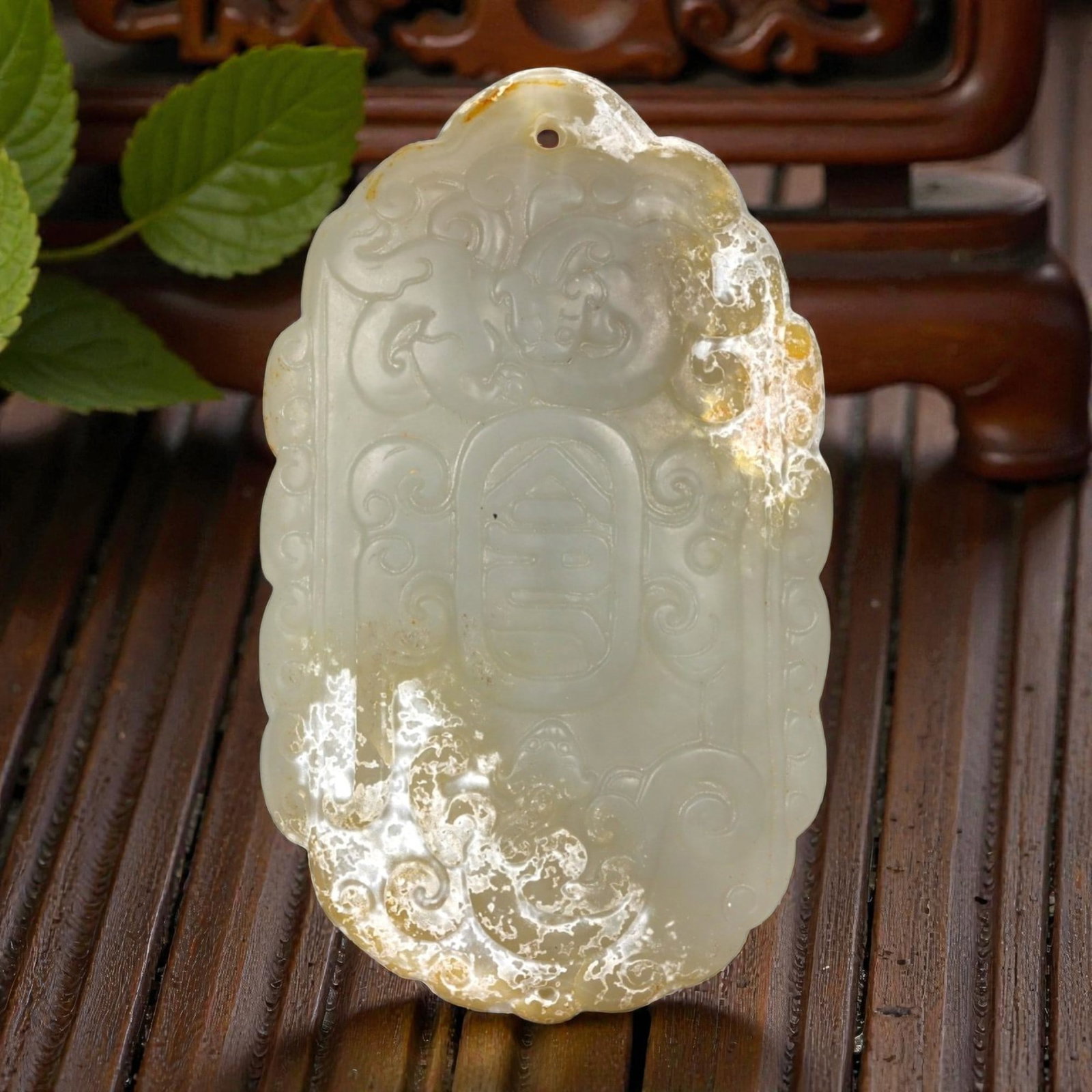 A Chinese Hetian Nephrite Jade Longevity Plaque, Qing Dynasty, 18th-19th Century, 26FA: Carved from pale celadon jade with areas of translucent milky tone and natural russet-brown inclusions, the plaque is of vertically oriented rectangular form with a rounded upper edge. The surface is 